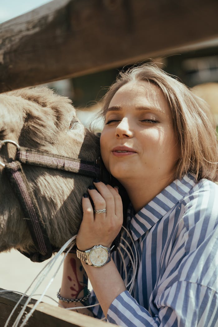 Woman in Blue and White Striped Long Sleeve Shirt Holding Black Horse